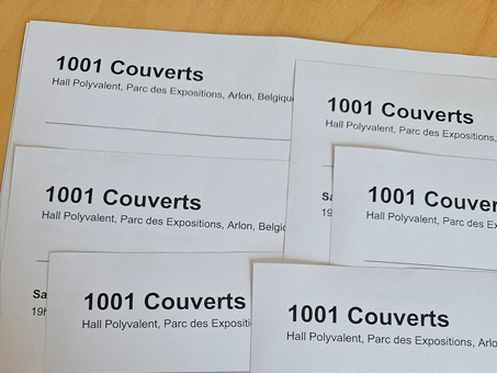 Papier étalé sur une table, "1001 couverts" écrit sur les feuilles.